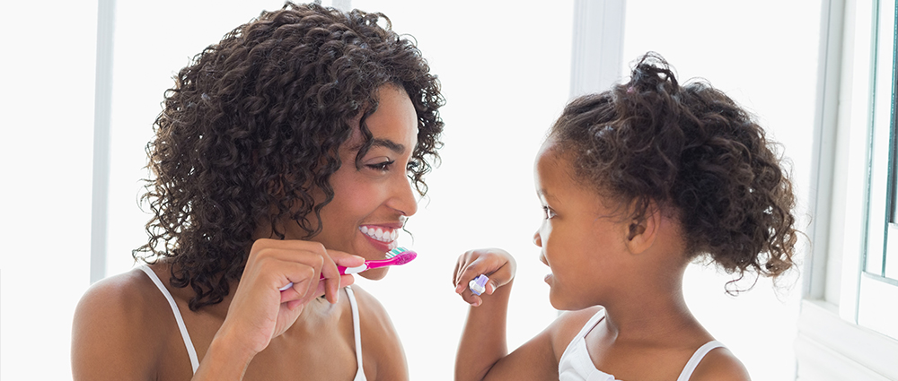 mom and daughter brushing teeth together