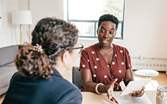african american woman speaking to another woman in an office