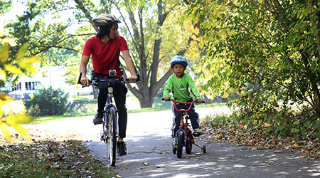 A man and child riding bikes on a trail path