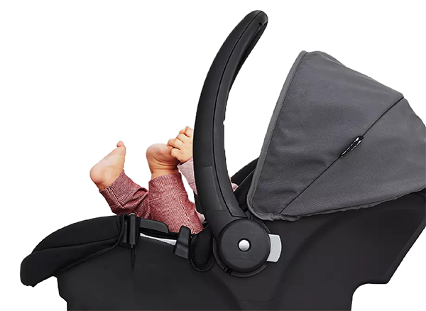 Infant car seat with legs and arm of a baby reaching out