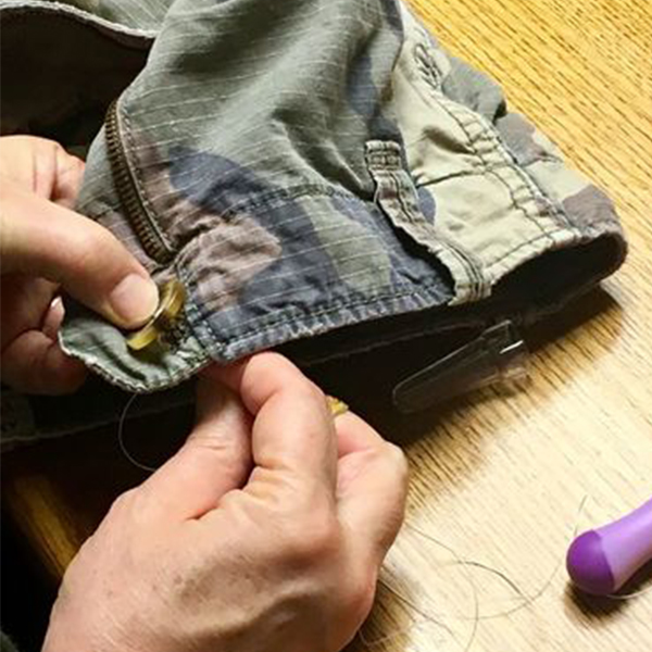 jacket button being sewn on by hand