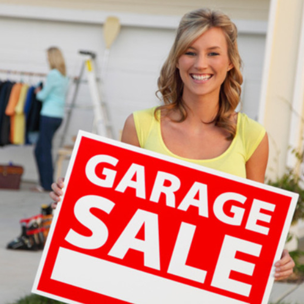 young woman holding 'garage sale' sign