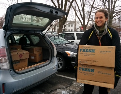 person putting a box of food in the trunk of a car