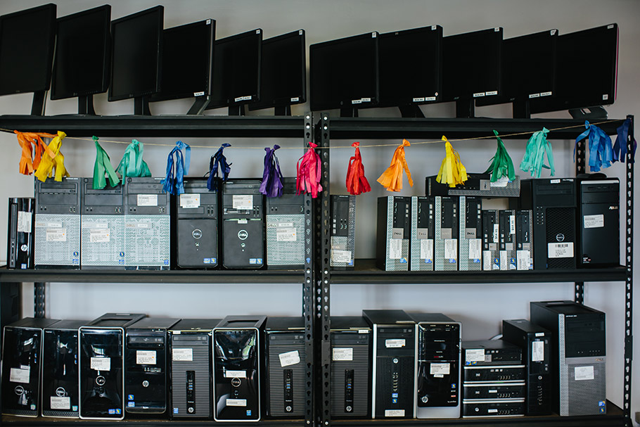 Monitors and desktop computers with rainbow tassels hanging on shelf
