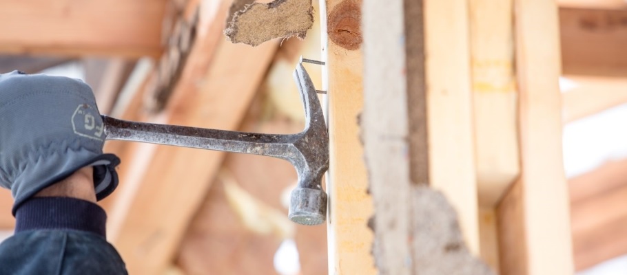 Close up of gloved hand with hammer removing nail from wood