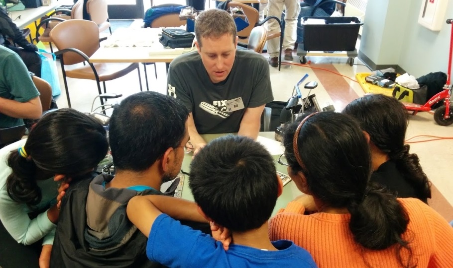 man showing people around a table how to fix something