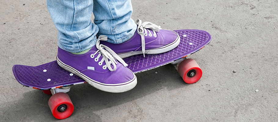kid sneakers and feet on a purple skate board