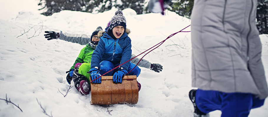 Kids smiling being pulled on a sled