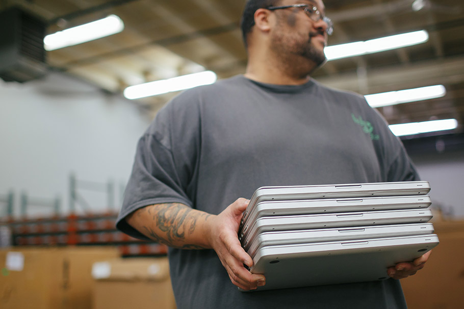 Man holding stack of closed laptops