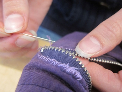 Closeup of hands sewing zipper