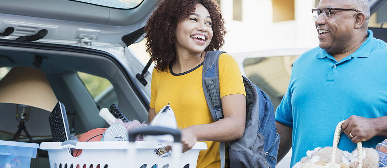 College student and father remove laundry baskets of student's items out of car trunk