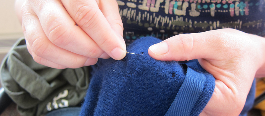 Woman sewing a patch into a sweater