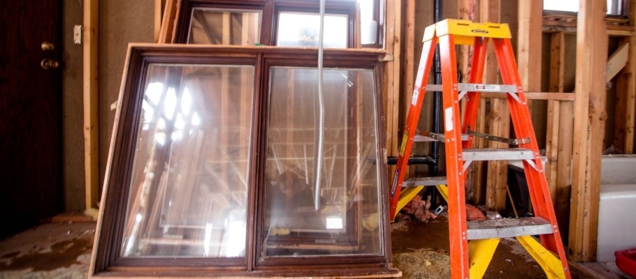 Salvaged windows next to a ladder at a demolition site