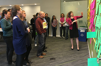 Group of people in a conference room standing at a wall discussing ideas