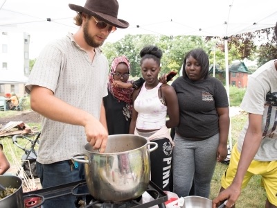 Man serves food to young people from a large pot