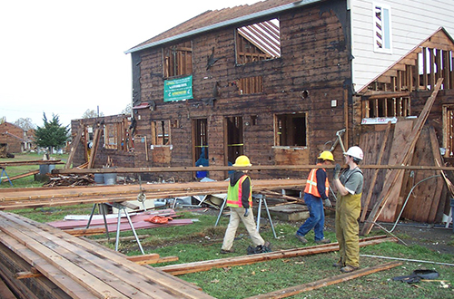 Construction workers hauling wood away from a house that's being deconstructed