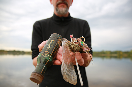 Man holding plastic litter standing by lake