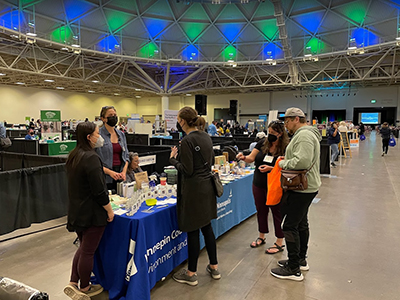 People at an indoor event at a Hennepin County table talking to staff