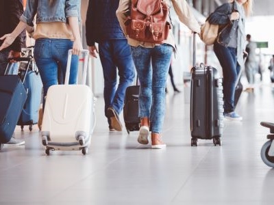 People rolling suitcases while walking away.