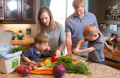 Parents with two young boys chopping vegetables in the kitchen