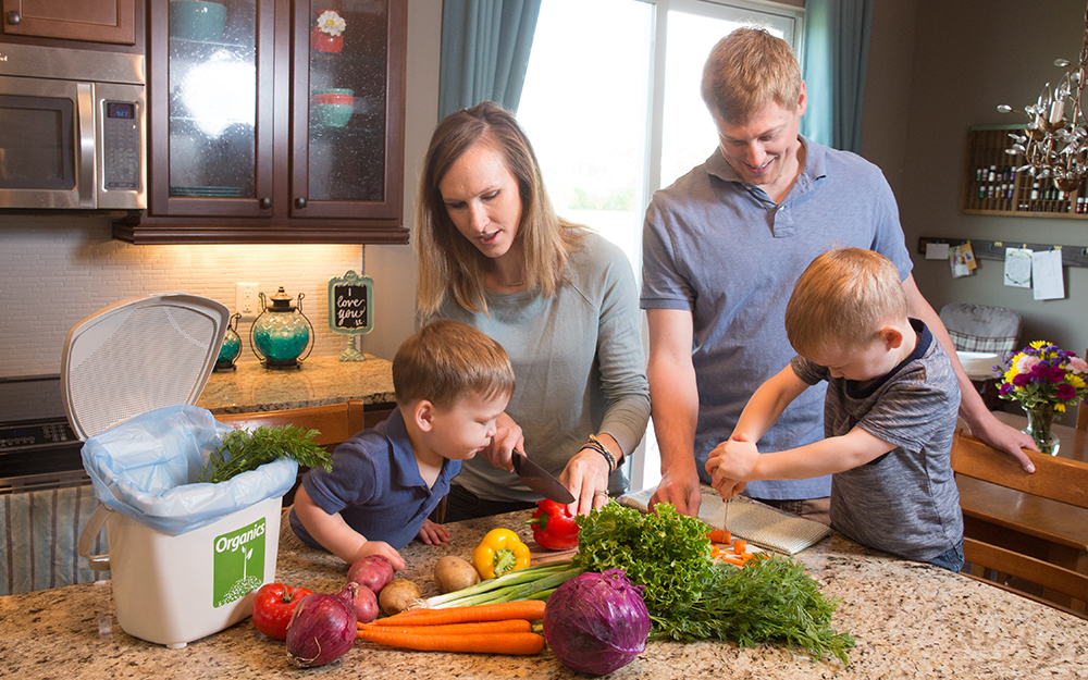 Parents with two young boys chopping vegetables in the kitchen