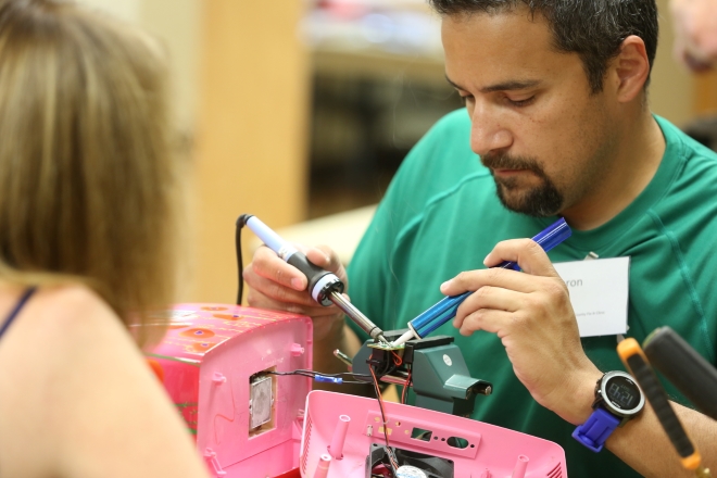Man fixing pink sewing machine