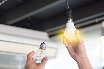 Man changing compact-fluorescent (CFL) bulbs with new LED light bulb.