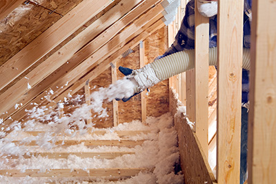 Worker adding spray insulation to attic.