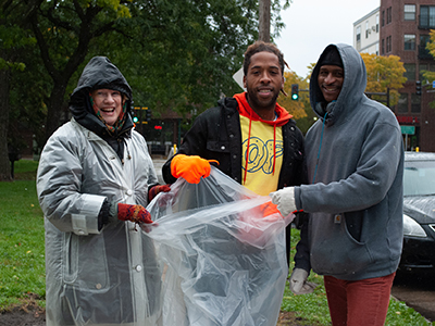 Три человека держат пластиковый пакет для уборки мусора