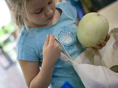 Girl putting melon in reusable bag