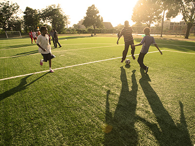 People playing soccer while the sun is starting to set