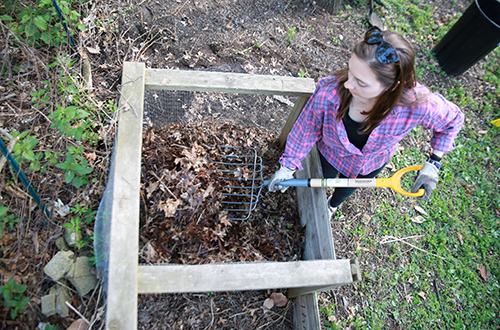 Woman with pitchfork turning compost pile