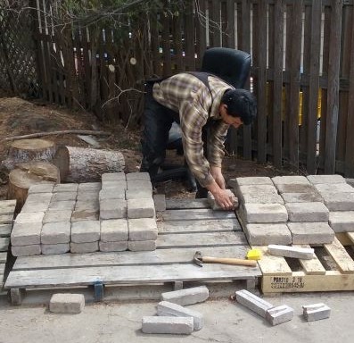 Man picking up a pavers from a stack of pavers on a pallet
