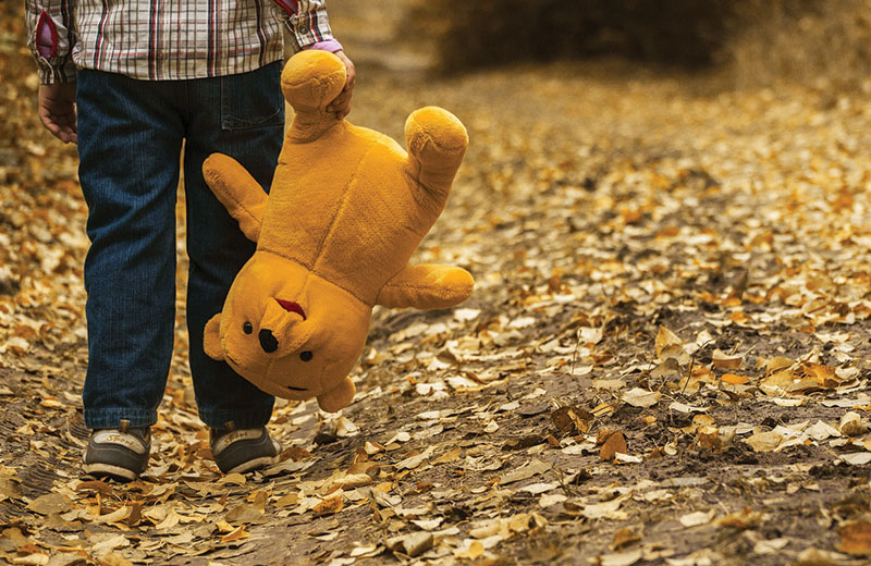 child outside holding stuffed animal bear