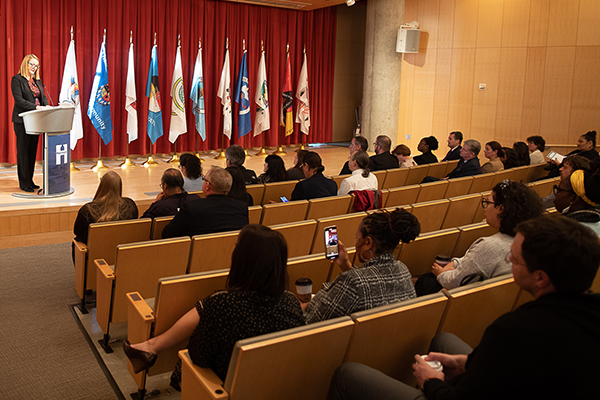 commissioner greene speaking with flags in background