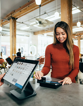 A woman using a point of sale in a hair salon. Tech Essentials offers guidance and technical support for small businesses in Hennepin County looking to keep up with digital change. This program is part of Elevate Hennepin. 