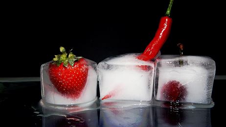 Photo of three ice cubes with berries and a chili pepper frozen in them