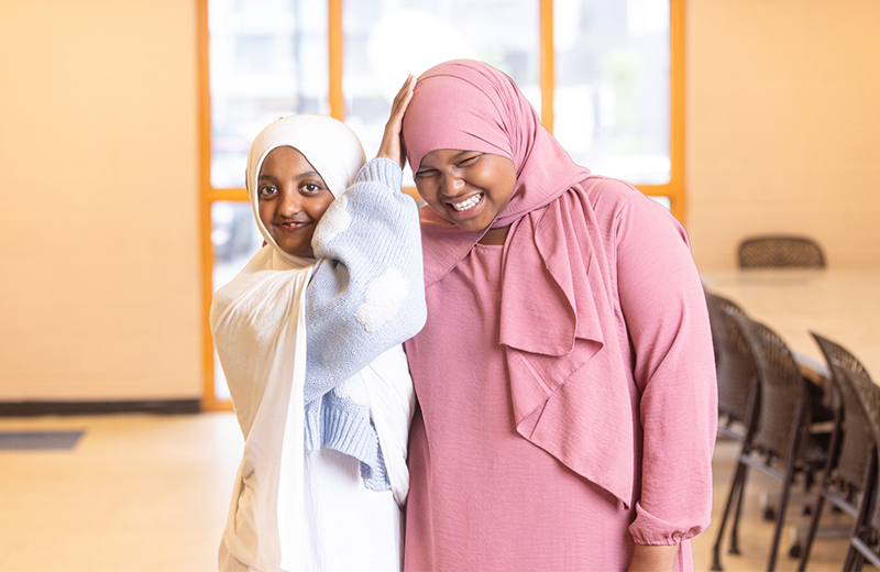 two girls laughing with each other inside