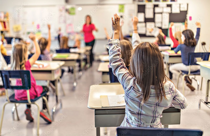 students sitting at their desks with their hands up