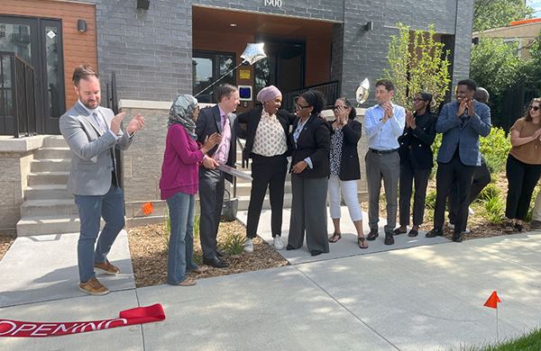 people clapping in front of building after ribbon cutting