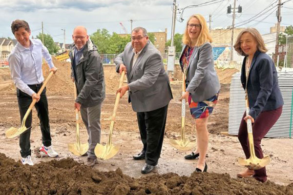 people outside shoveling dirt for the groundbreaking