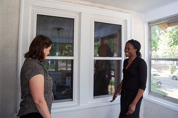 two women outside the house standing by windows