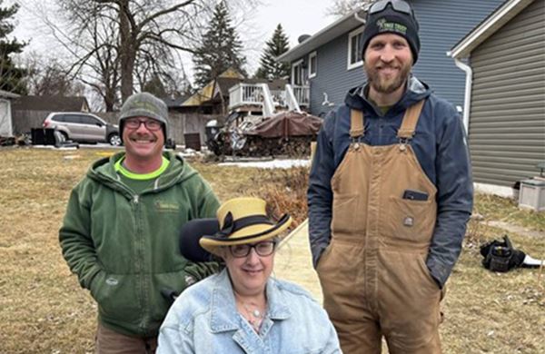 women in wheelchair and two men standing behind her outside
